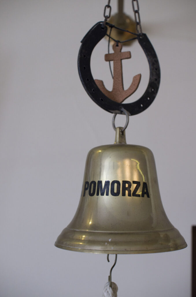 Mosiężny dzwon z napisem „Pomorza", zawieszony pod podkową z kotwicą